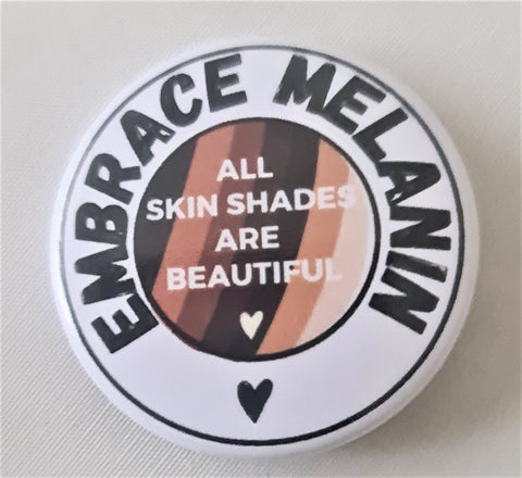 Embrace Melanin white round badge with the words, all skin shades are beautiful on the embrace shades globe.